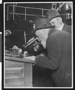 Astronomers in an observatory who appear to be looking through the eyepiece of a telescope, ca.1920-1930
