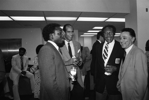 Elbert T. Hudson talking with colleagues during a Broadway Federal Savings and Loan event, Los Angeles, 1984