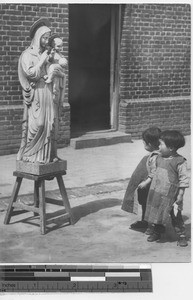 Young children looking at a wooden statue at Fushun, China, 1936
