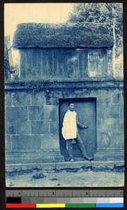 Man standing in a niche in a wall of dressed stone blocks, Madagascar, ca.1920-1940