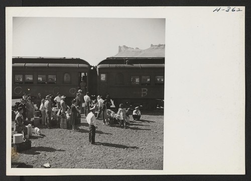 Transferees bound for Heart Mountain from Tule Lake on trip 24 wait with their luggage for the partially loaded train to pull up to their assigned coach. Photographer: Mace, Charles E