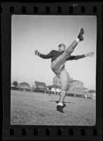 Bud Langley, USC football player, kicking a football, Los Angeles, 1935
