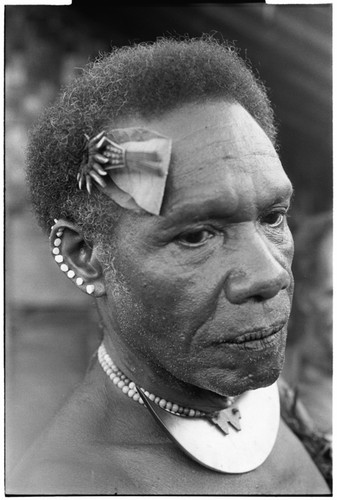 Man with dafi pearshell neck ornament, and plaited fari (spilt) comb with kwaloi'a porpoise tooth star, and leaf bespelled to protect him from sorcery at the feast