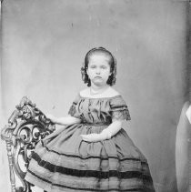 Young girl seated on arm of chair