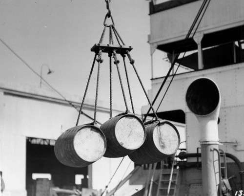 Closeup view, liquor barrels hoisted by ropes
