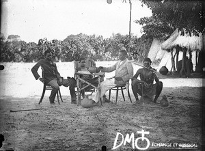 African men and boy sitting at a table, Antioka, Mozambique, ca. 1901-1915