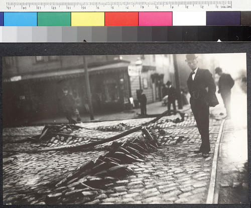 [Man posing beside buckled streetcar rails and ruptures in street. Unidentified location.]