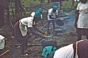 Nordveststiftet, Tanzania, 1984. Fra en lektion i bagning på Ntoma Husholdningsskole. Der anvendes store jernskåle, den ene fyldes med sand, sættes over bålet en times tid, så det varmes op, hvorefter en anden jernskål lægges over. Nu er der klar til at bage brød eller en kage