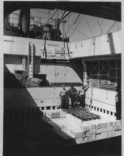 3 crewmen atop produce crates [prunes, raisins]; shadows