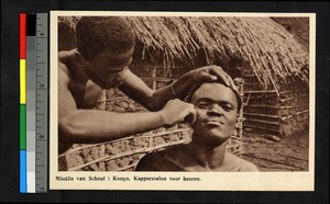 Man sitting while a barber tends his hair, Congo, ca.1920-1940