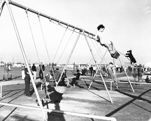 A group of children playing on a swing set in a Los Angeles playground