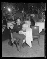 Singer Eartha Kitt, seated in empty nightclub in Los Angeles, Calif., 1953