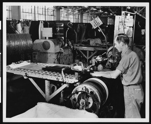 Factory worker spooling rubber on a conveyor belt, ca.1945