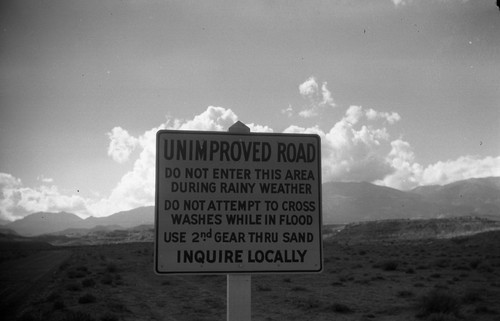 Sign: Highway 95, 15 miles East of Hanksville on road to Hite and Blanding, Utah, with sign, "Unimproved Road, Do Not Enter In Rainy Season, Use second Gear in Sand, Make Local Inquiry," SV-1301