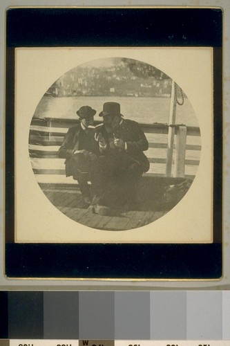 [Man and boy reading on dock]