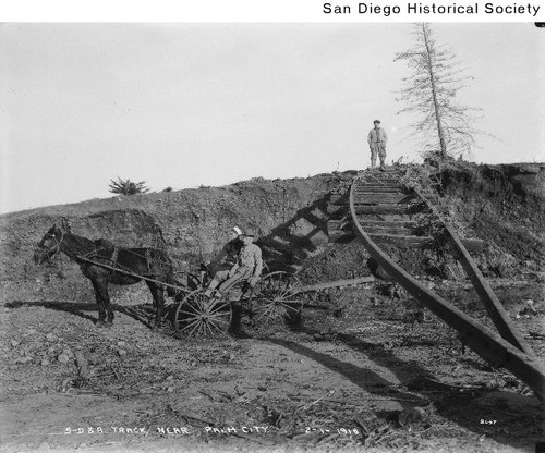 Two people in a horse-drawn wagon near San Diego & Arizona railroad tracks damaged during the 1916 flood