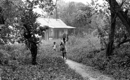 Woman walking with metal bucket on her head, San Basilio de Palenque, 1976