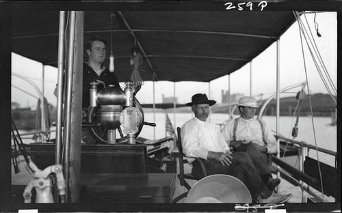 Man at helm with two men sitting nearby, Bonnie Doon (steamcruiser yacht). [negative]