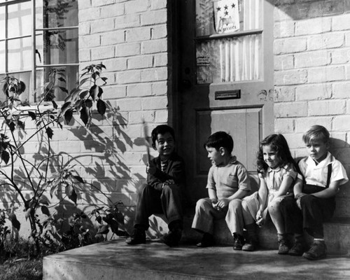 Children sitting outside their apartments