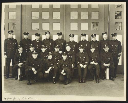 Uniformed personnel in front of a unnamed fire station