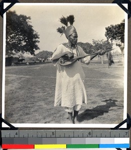 Beggar musician in a feathered hat, Shendam, Nigeria, 1923