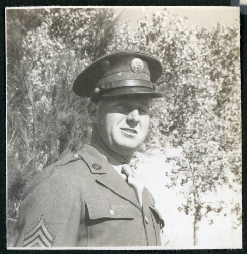 Photograph of a army soldier standing in front of trees
