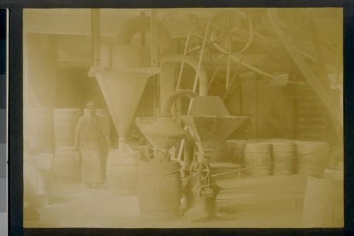 [Factory worker loading barrels.]