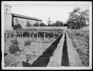 Mission Santa Barbara, showing stone aqueduct and vineyard, California, 1898