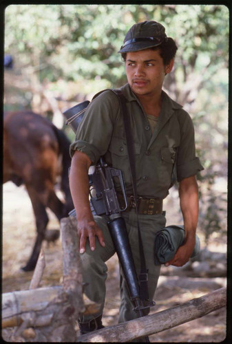 A guerrillero in uniform stands outside close to a mule, La Palma, 1983