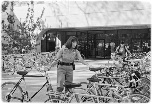 Campus police officer checking bicycles in front of Geisel Library