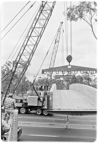 Pedestrian footbridge over U.S. Highway 101 hoisted into place by two cranes