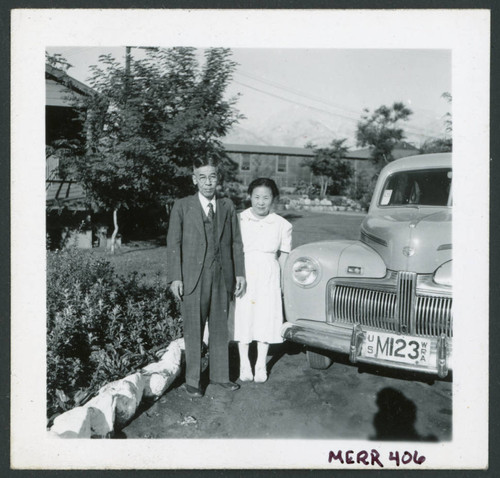Photograph of a couple posing in front of a car near the Manzanar hospital