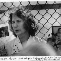 Mercy Gehrig, 57, stands beside photos of children placed on the Mather Air Force Base fence