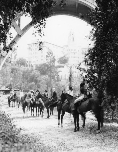 Horseback riders under the bridge