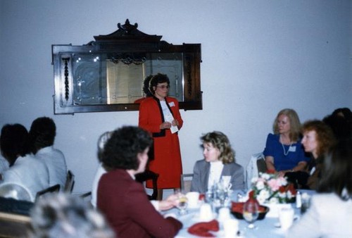 Woman addressing women sitting at dining tables