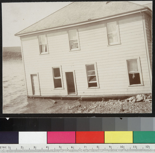 House thrown into Tomales Bay at Point Reyes Station. High tide washes in at lower windows. [Marin County.]