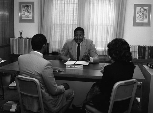 Charles R. Anderson sitting at his desk with clients at Broadway Federal Savings and Loan, Los Angeles, 1986