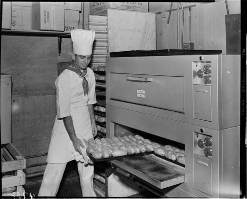 Chef taking tray of baked potatos out of a baking oven