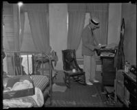 A. J. Fitzgerald, investigator, searching the room of William F. McKee who committed suicide, 1935