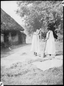 Two girls stamping maize, Arusha, Tanzania, ca.1907-1930
