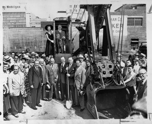 At the controls of steam shovel with Actress Celeste Holm standing by is Governor Warren at groundbreaking ceremonies for Statler Center