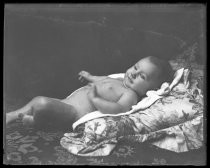 Portrait of a nude baby lying on a cushion