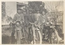 Three men seated on motorcycles