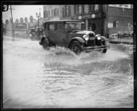 Automobile driving down flooded street during rainstorm, [Los Angeles County?], 1926