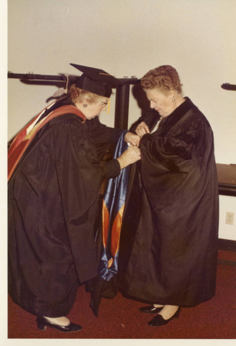 Mrs. Pepperdine being assisted with her robing