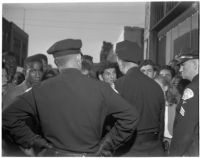 Three policemen face a crowd on young people on a city street, Los Angeles