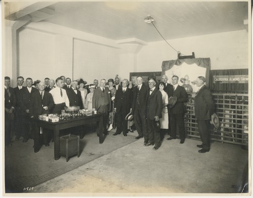A-13, "At almond plant in Sacramento." T. C. Tucker, Senator Hiram W. Johnson, and George W. Pierce, Jr., in center; McCurry Foto Company