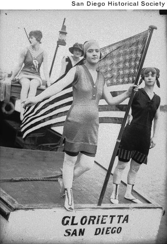 Four women in bathing suits, one holding a U.S. flag, aboard the Glorietta