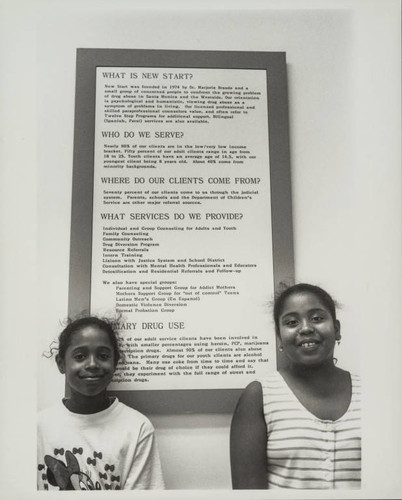Two young women in front of a New Start mission statement sign, Santa Monica, Calif