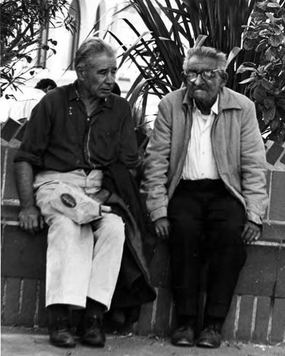 Two old men sitting on plaza bench near kiosko